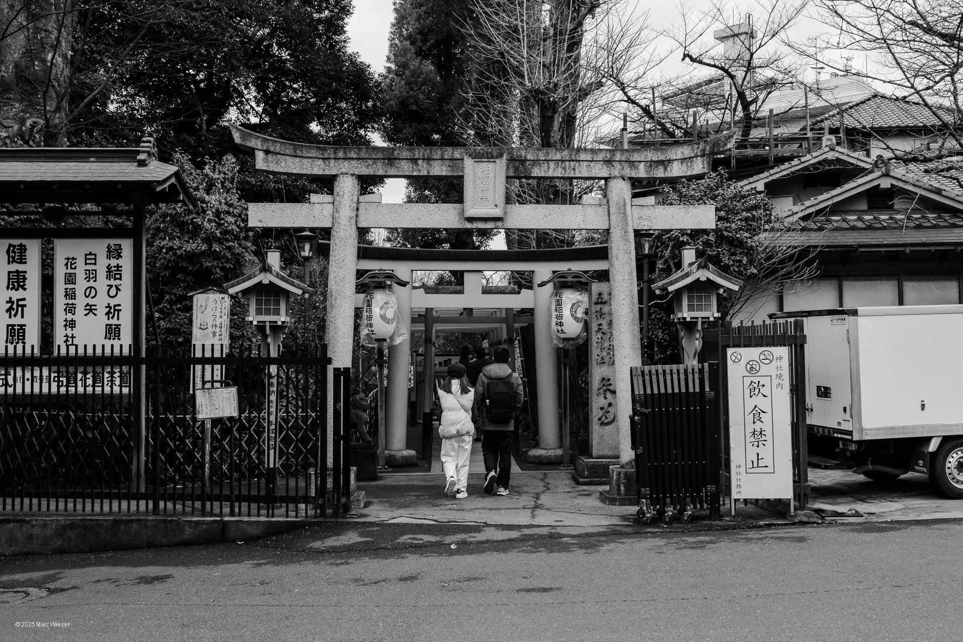 Photo en noir et blanc d’un couple entrant dans un temple dans une rue de Tokyo